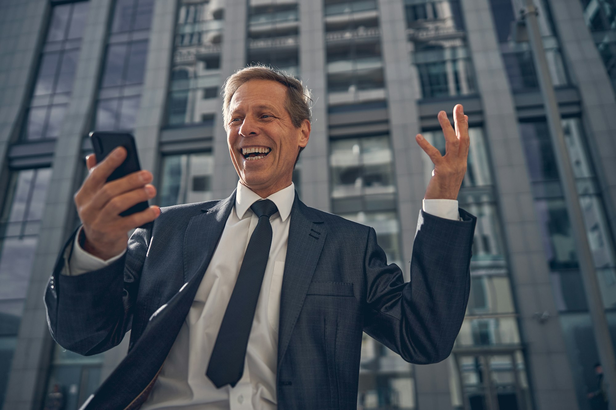 Happy businessman using smartphone on the street